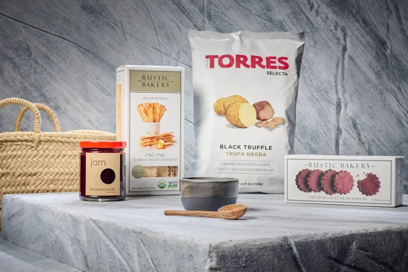 Snack packaging, a jar, and a basket arranged on a marble slab, studio product photography